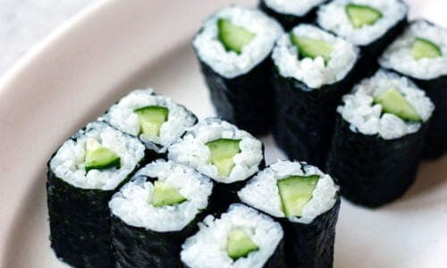 Slices of cucumber Kappa Maki sushi roll on a wooden plate