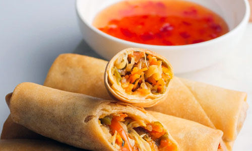 Golden crispy vegetable spring rolls served with dipping sauce
